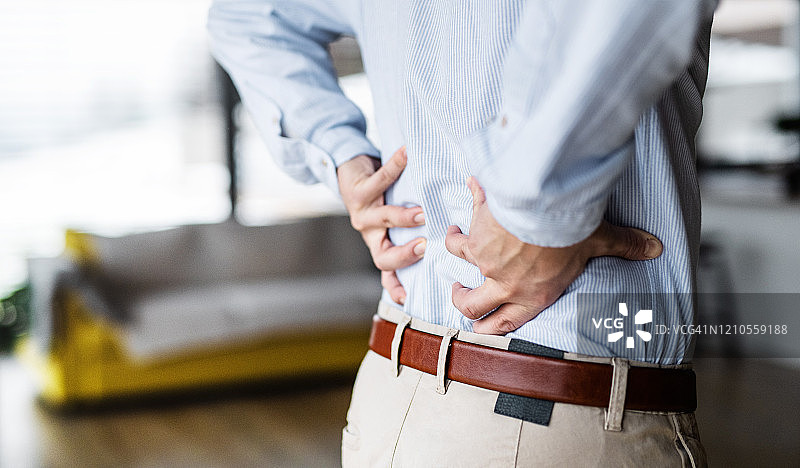 在家中感到背痛的商人图片素材