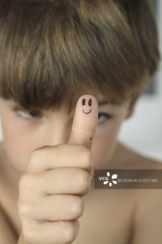 男孩用画在手指上的人脸做OK手势图片素材