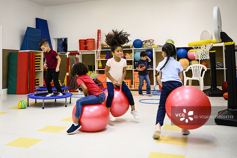 微笑的西班牙裔小学生在游戏室里锻炼图片素材