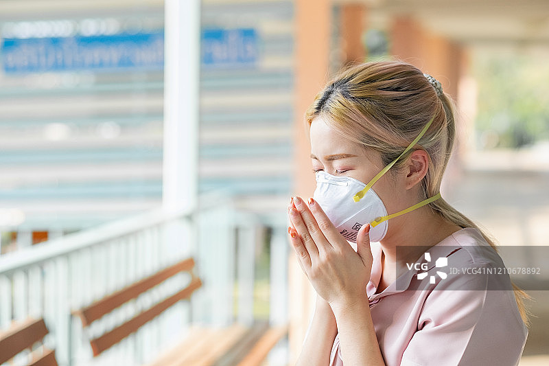 戴口罩的亚洲女性咳嗽，手捂口罩图片素材