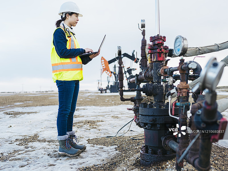 使用笔记本电脑的女石油工人图片素材