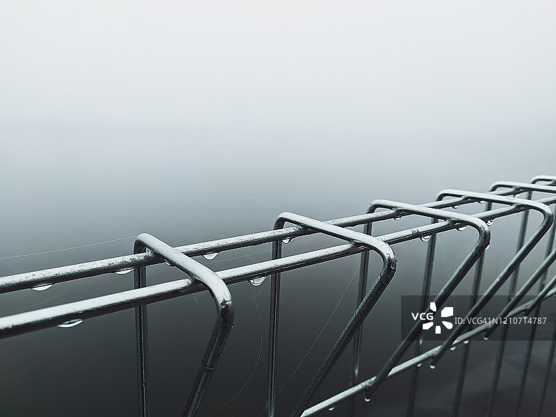 水库中铁栅栏的雾景特写图片素材