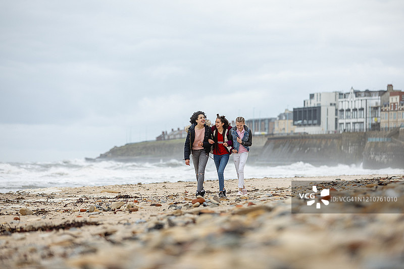 沿着风大的海岸行走的少女图片素材