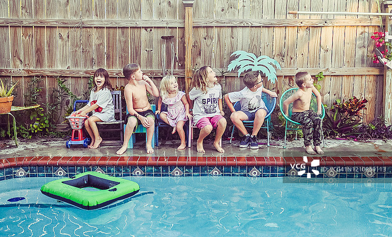 一大群不同年龄段的孩子坐在游泳池边嬉戏图片素材