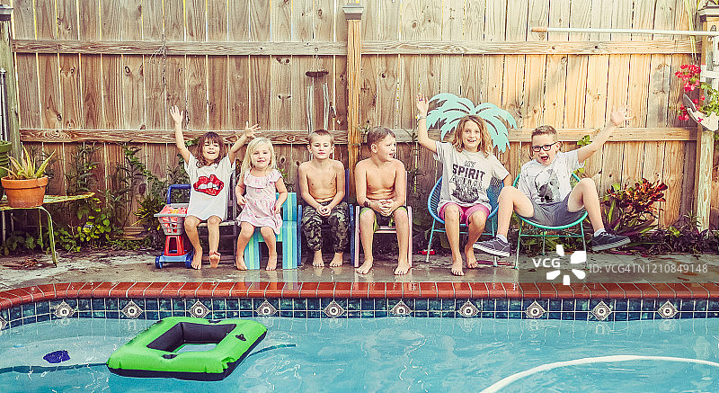 一大群不同年龄段的孩子坐在游泳池边嬉戏图片素材