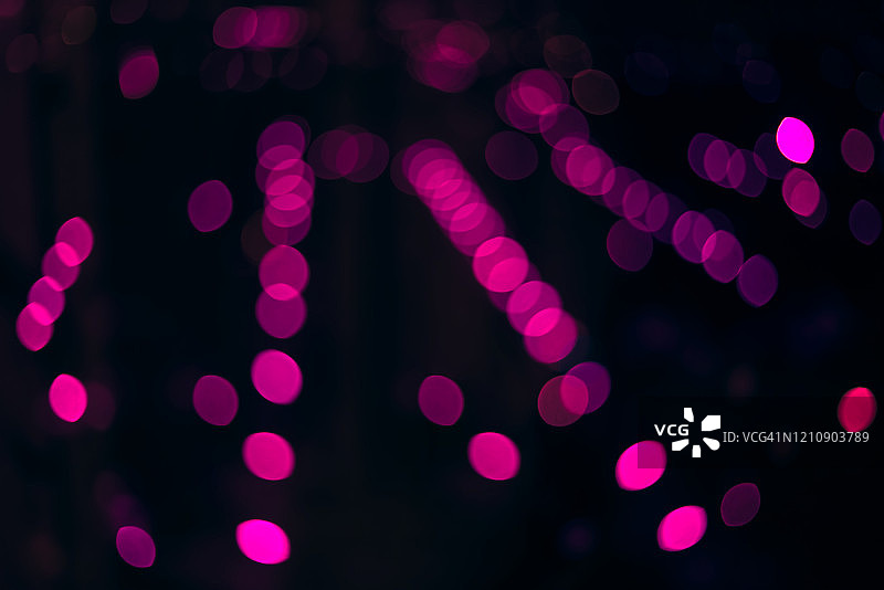 夜晚灯光下的粉色散景圆圈，类似于冬季夜晚的背景照片图片素材