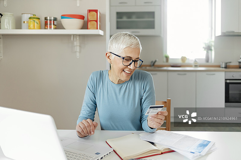 使用信用卡进行网上银行操作的退休人员图片素材