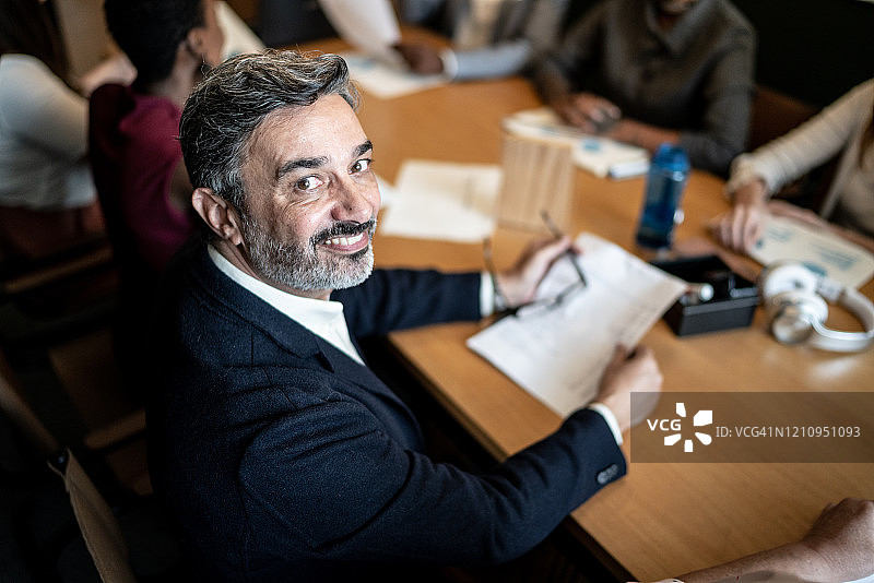 中年商人在会议室里坐着的肖像图片素材