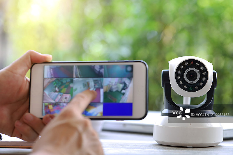 手按手机、手表和监控摄像头图片素材