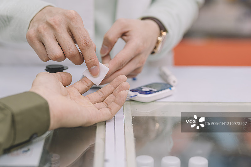 中国药剂师为男患者做糖尿病检测准备图片素材