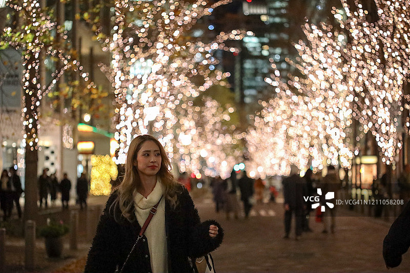 年轻漂亮女人在圣诞灯饰中行走图片素材