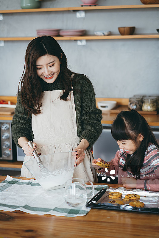 快乐的小女孩和妈妈在厨房一起做饼干图片素材