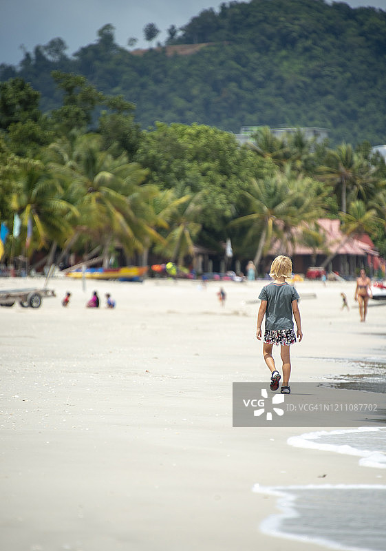 在马来西亚兰卡威海滩上行走的金发男孩图片素材