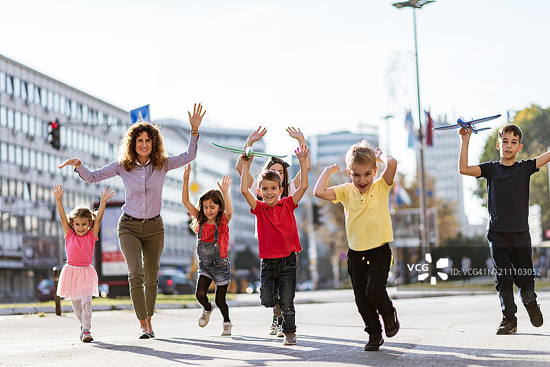 孩子们在城市街道上快乐地奔跑玩耍图片素材
