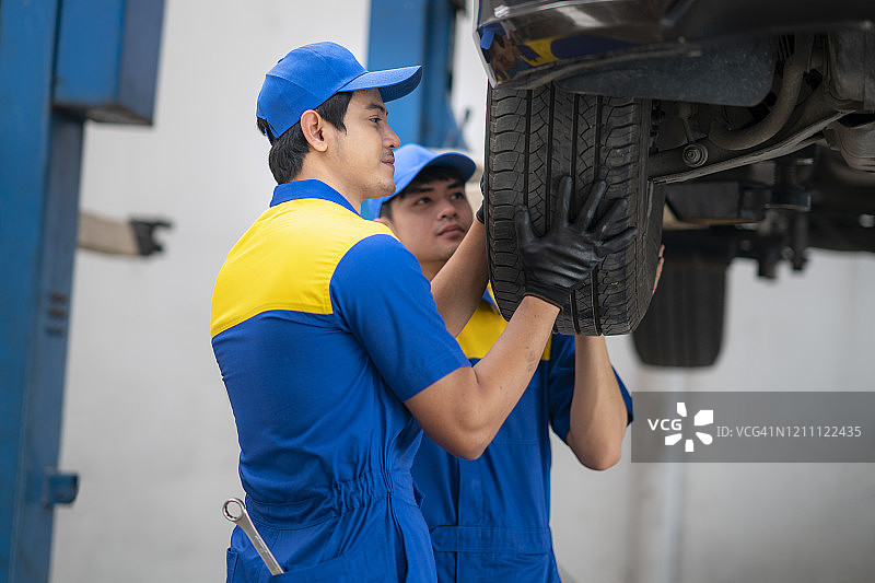 亚洲汽修工用气枪更换汽车车轮图片素材