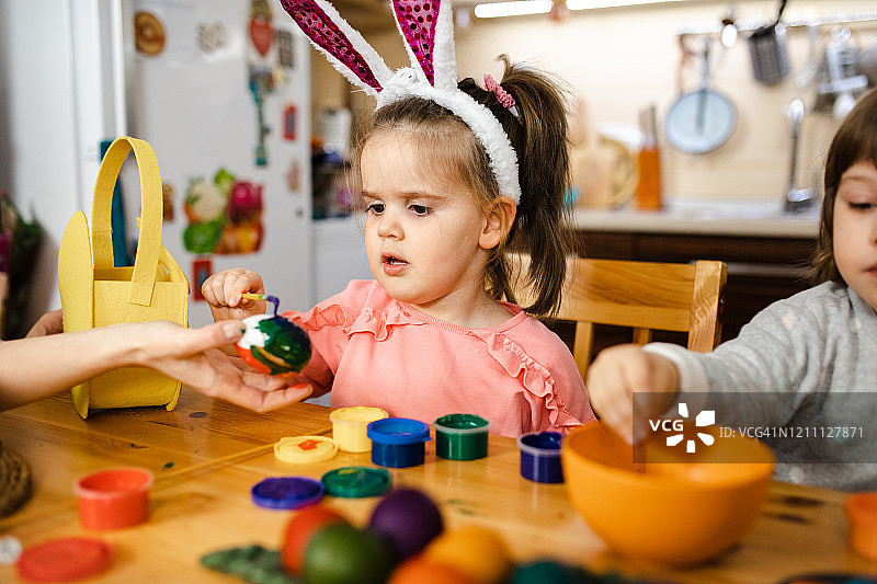 专注的女童用蛋彩画为她的复活节彩蛋着色图片素材