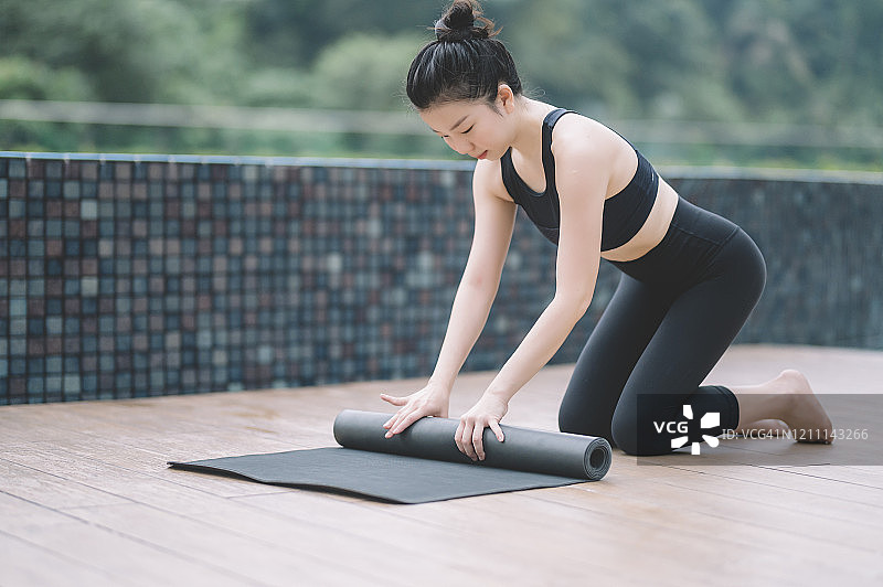 瑜伽教练在她家前院卷起瑜伽垫图片素材