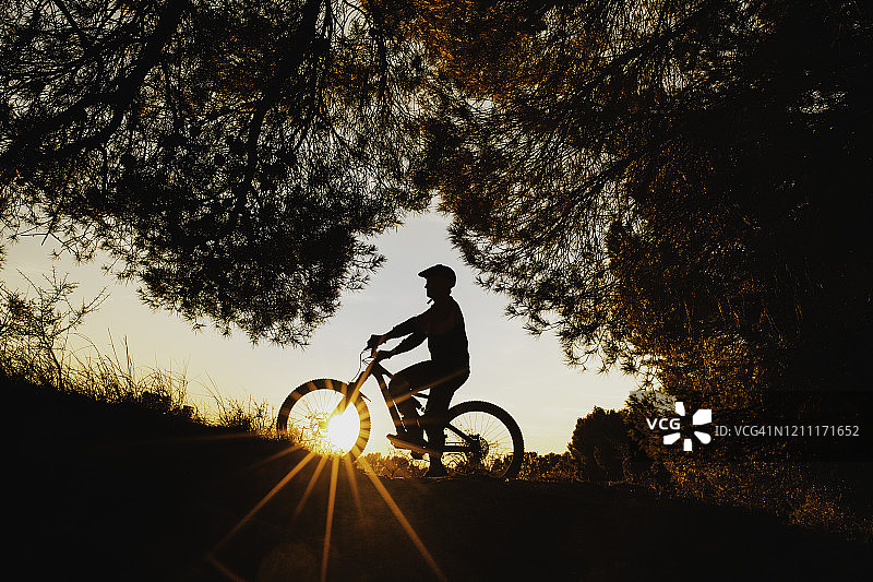 骑自行车的男人看着橙色的日落图片素材