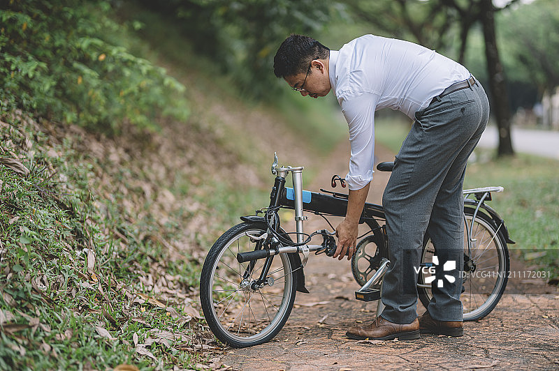 骑折叠自行车通勤的亚洲职场人士图片素材