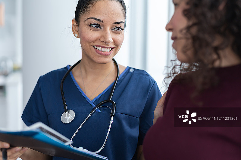 正在用医学图表为病人讲解病情的美丽女医生图片素材