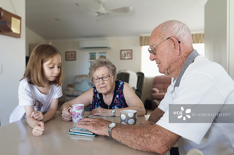 孙女和祖父母一起玩平板电脑图片素材