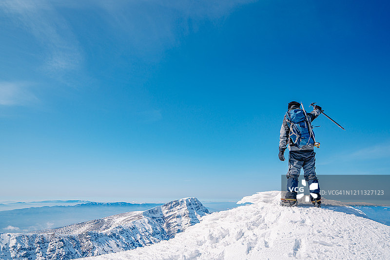 在冬日高山之巅张开双臂庆祝成功的老年登山者图片素材