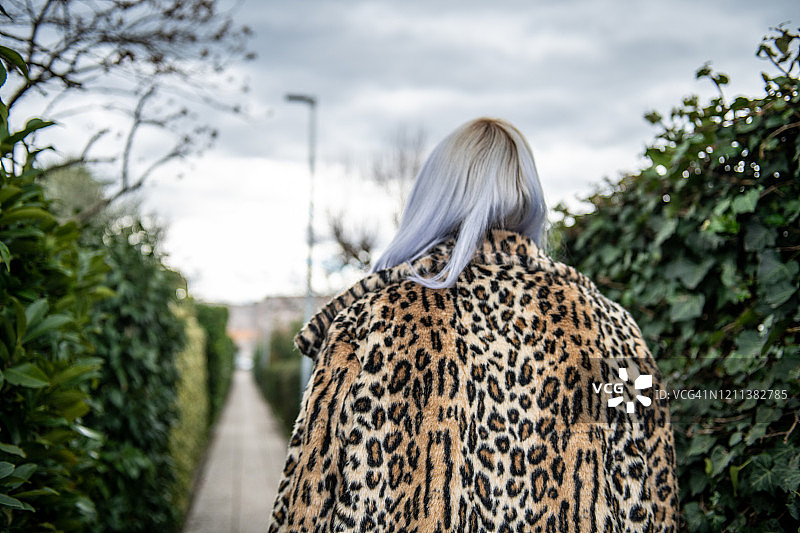 身穿仿豹纹毛皮大衣的彩色头发女人的背影图片素材