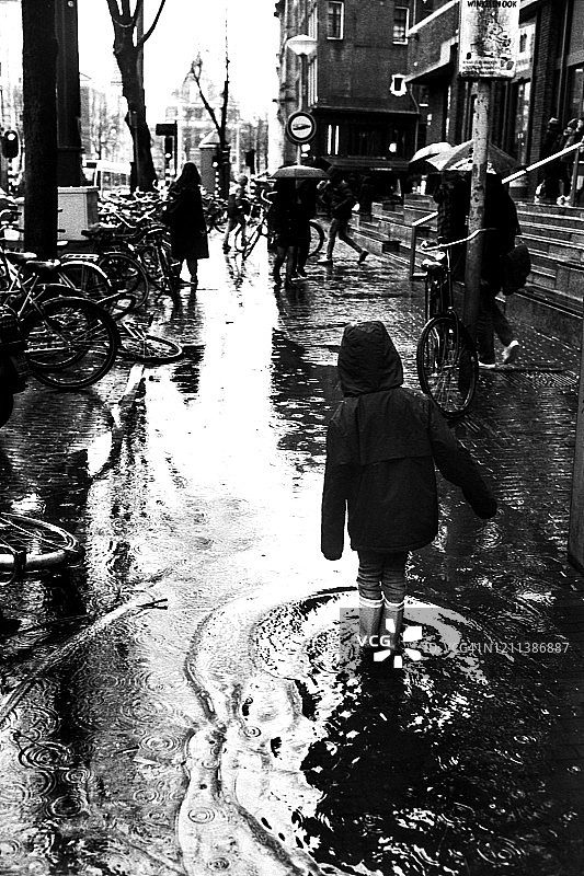 儿童在雨中穿过水坑图片素材