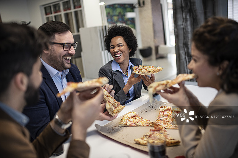 气氛活跃的商务团队在办公室吃披萨图片素材