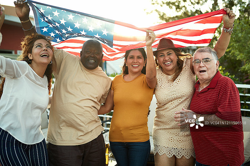 举着美国国旗的微笑的朋友们的肖像图片素材