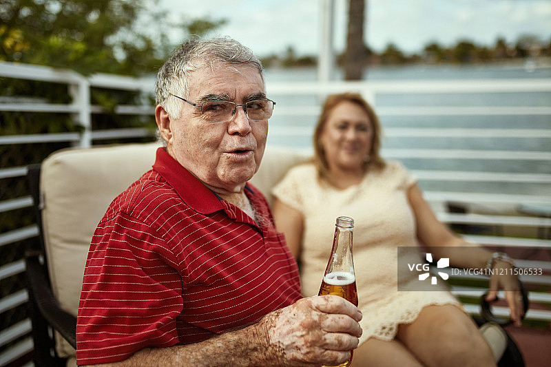 拿着啤酒转向镜头的西班牙裔老年男性图片素材
