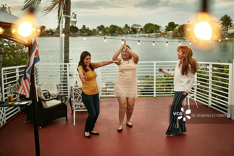 50多岁的西班牙裔女性朋友在派对上欢笑跳舞图片素材
