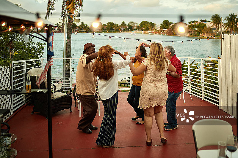 在佛罗里达州阳台上黄昏时跳舞的中年和老年朋友图片素材