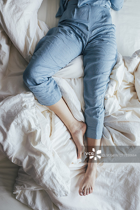 蓝色睡衣女子在床上睡觉的腿部腰部以下镜头，俯视图图片素材