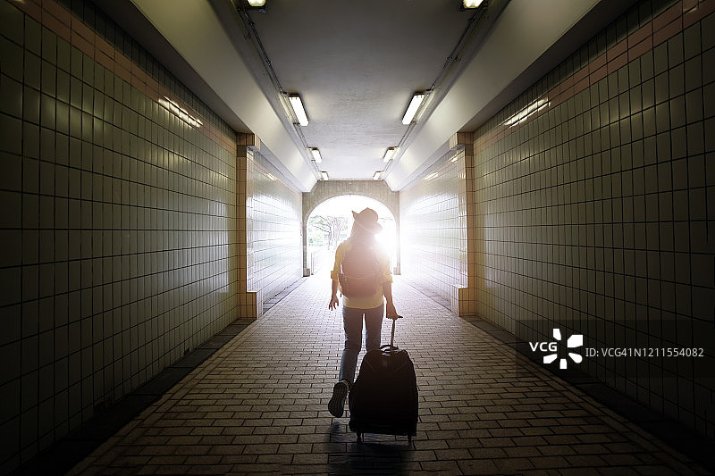 年轻女子背着背包和帽子前往新加坡市中心的背影。新加坡旅行概念。图片素材