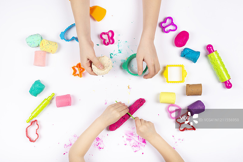 小女孩用彩色橡皮泥在白色背景上玩耍图片素材