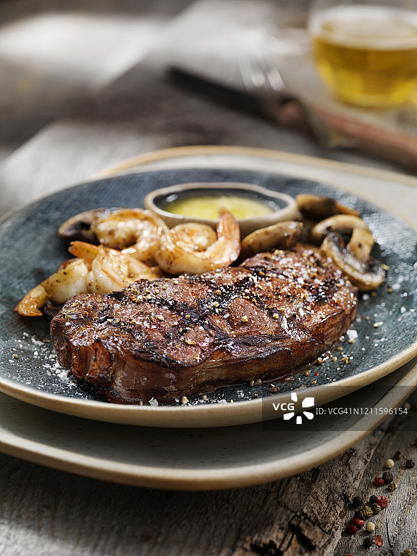 配有烤虾、蘑菇和香草蒜蓉黄油的五分熟西冷牛排中景图片素材