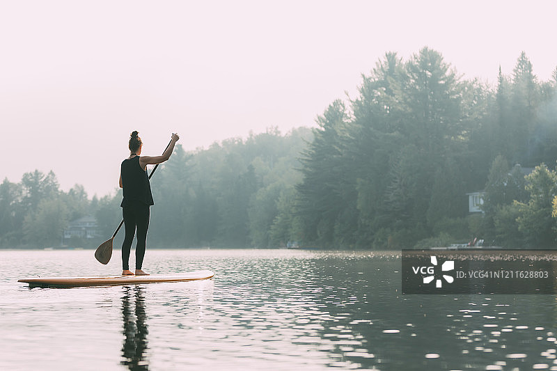 年轻女人在平静的湖面上划桨图片素材
