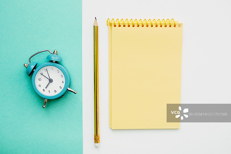 时间管理概念：蓝色复古闹钟、铅笔和黄色记事本图片素材