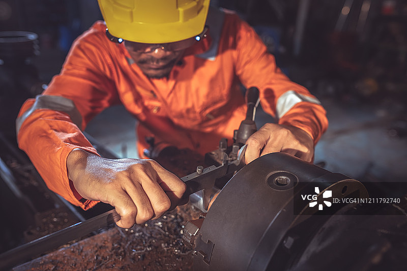 车床工人用卡尺测量金属工件尺寸图片素材