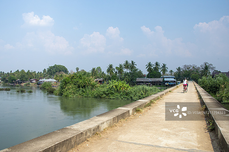 年轻女性游客骑自行车在Don Det和Don Khon群岛，老挝图片素材