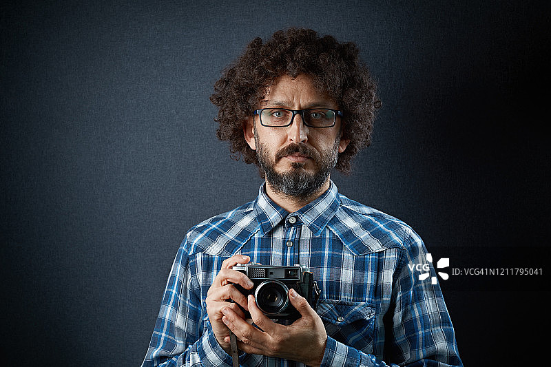 留着卷发的胡子的时髦男子拿着老式相机图片素材