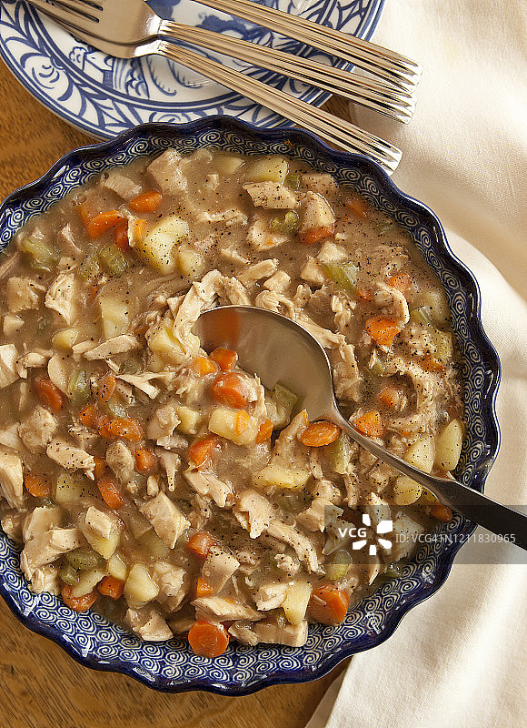 砂锅鸡肉或法式白炖鸡，配有餐勺和餐盘，放在木桌上图片素材