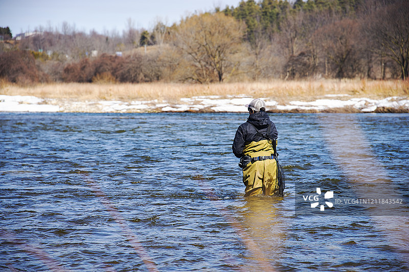 冬日傍晚，渔夫在河中捕捞虹鳟鱼图片素材