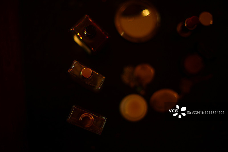 黑色背景上金色阳光下的香水瓶、项链和化妆品图片素材