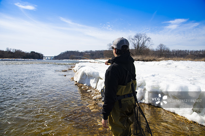 在冬末的一天，一位渔夫正在钓虹鳟鱼图片素材