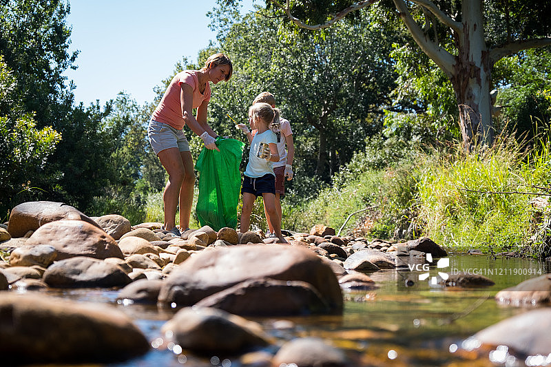 一家人从河里收集可回收物，学习可持续发展图片素材