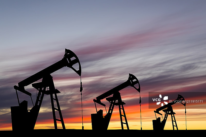日落背景下的抽油泵。世界石油工业图片素材