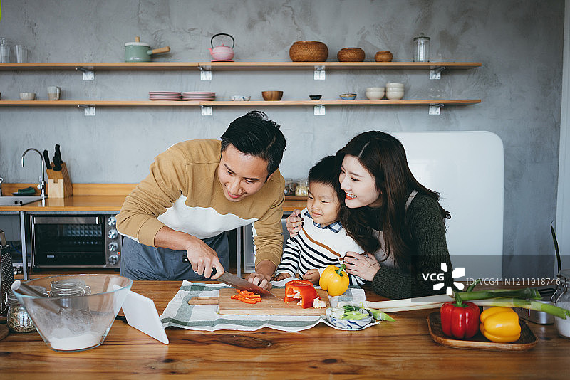 幸福的三口之家在厨房用平板电脑一起准备食物图片素材