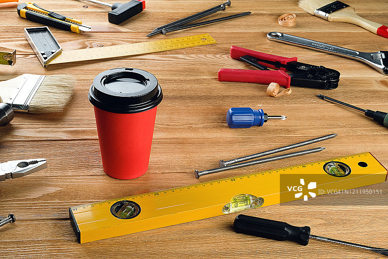 一次性杯中的茶或咖啡，木桌上的建筑或家居维修工具，工头或木匠的工作场所小吃或休息图片素材